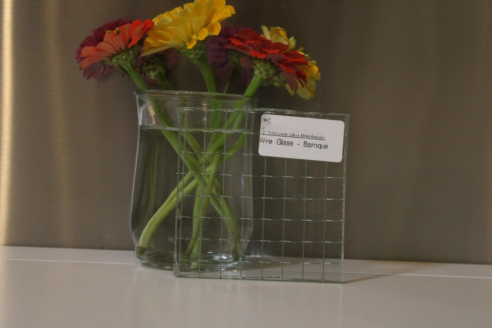 Flowers in a glass vase with crystals, placed on a white surface against a plain darker background.