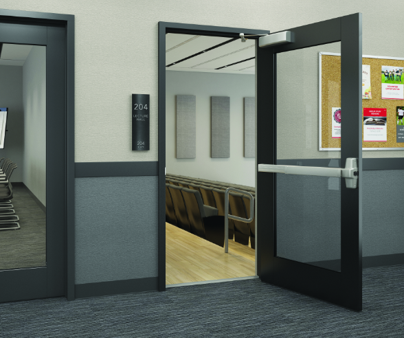 Open door to lecture hall with chairs and wall-mounted acoustic panels, adjacent to a hallway with a bulletin board.