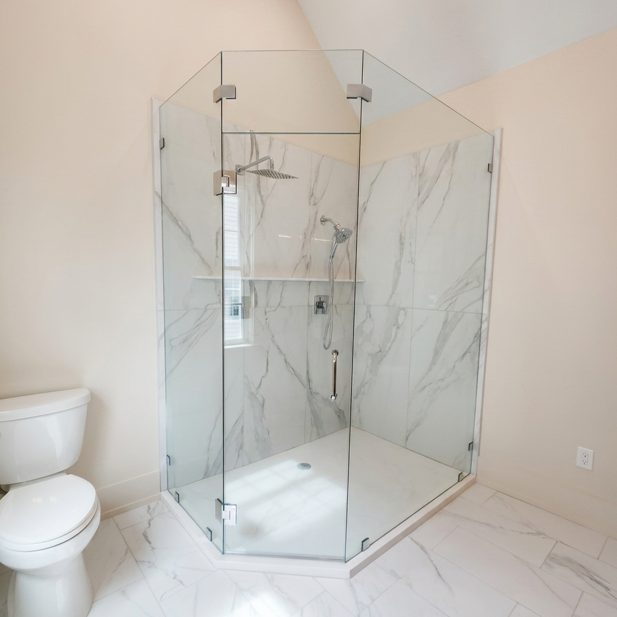 Modern bathroom with a glass shower enclosure and marble walls, with a toilet nearby.