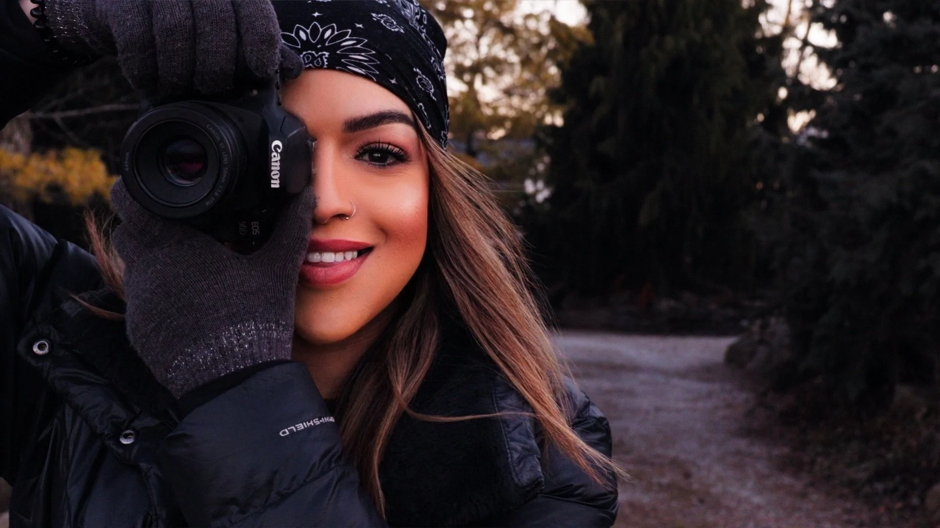 Seleste Loparo , filmmaker and photographer, holding a canon camera outdoors at sunset.