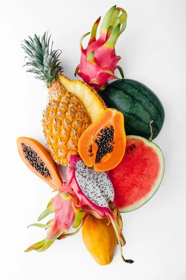 Assorted tropical fruits including pineapple, watermelon, dragon fruit, papaya, and mango on a white background.