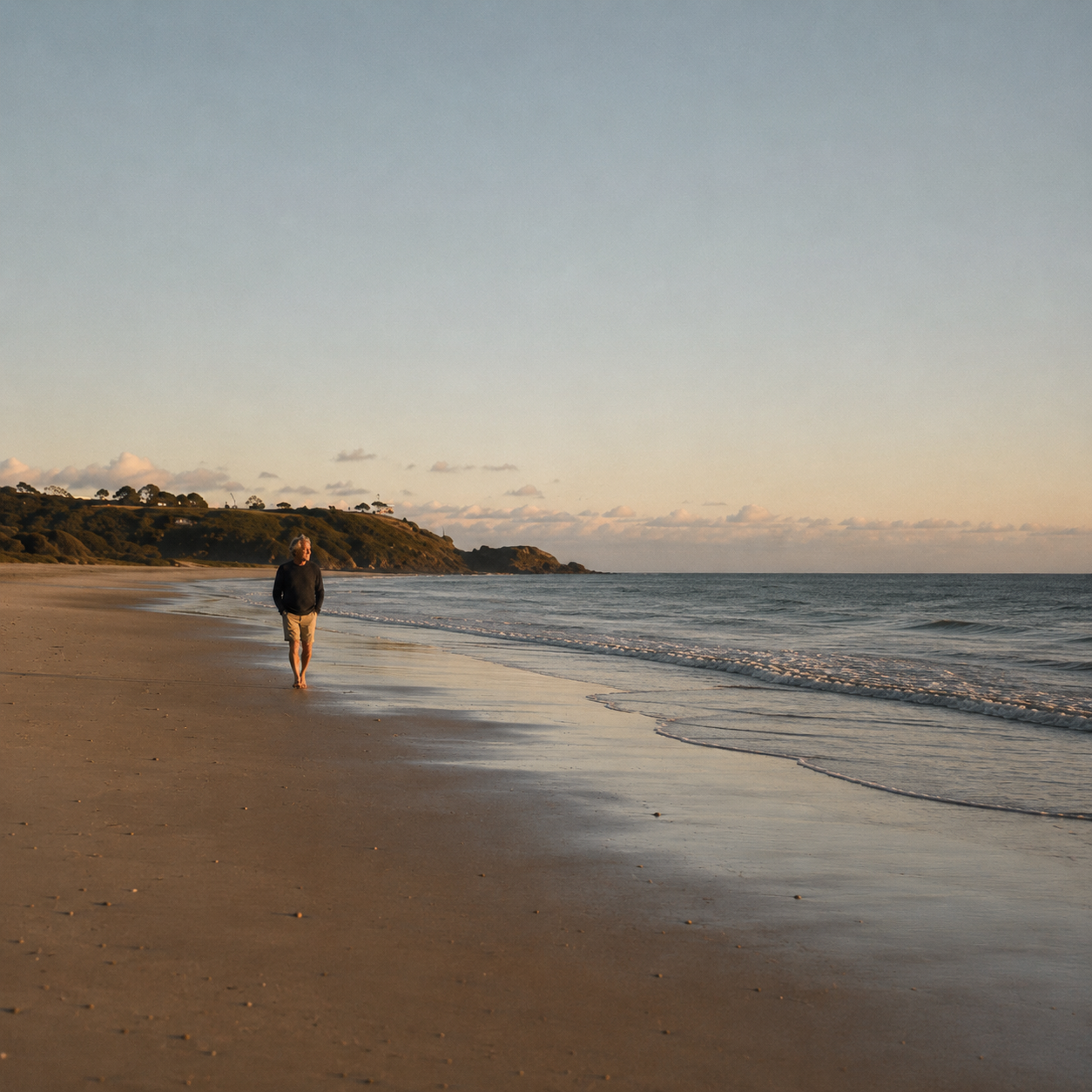 A person walking alone along the beach at sunset.