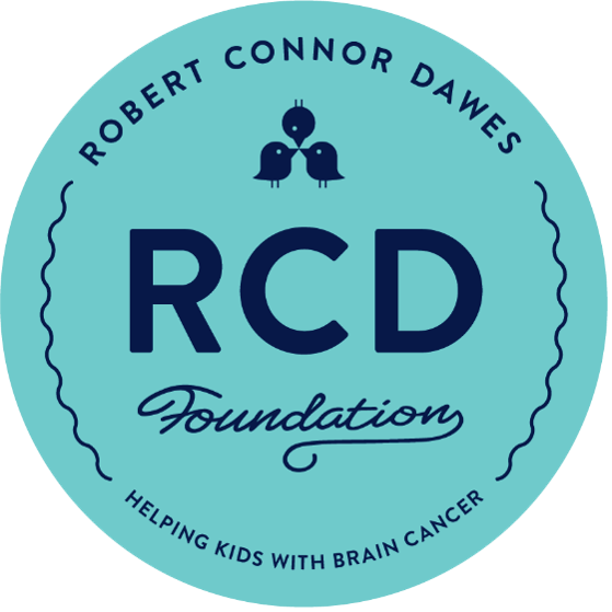 Circular logo for RCD Foundation with blue background, featuring two stylized birds above the letters "RCD" and the text "Robert Connor Daws Foundation" around the top, and "Helping Kids with Brain Cancer" around the bottom.