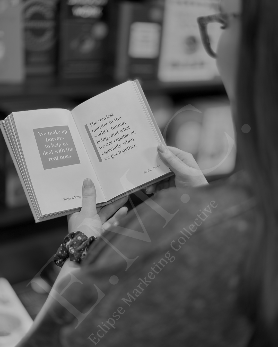 A person holding an open book showing quotes from Stephen King, Jordan Peele, and other authors in a bookstore.