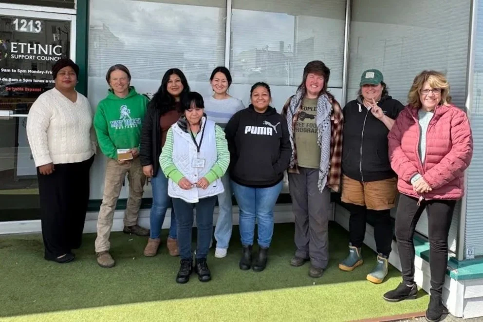 Group of nine people posing outside an ethnic support council building