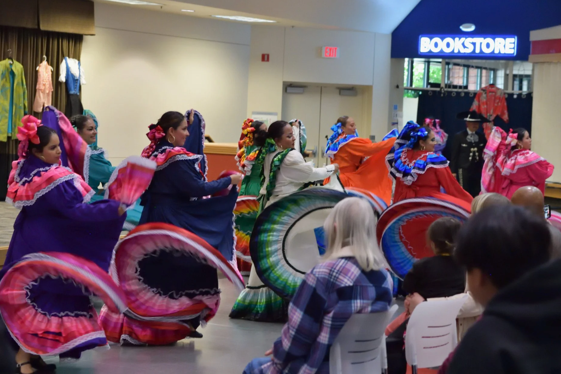 Mexican folkloric dancers performing in colorful traditional dresses before an audience