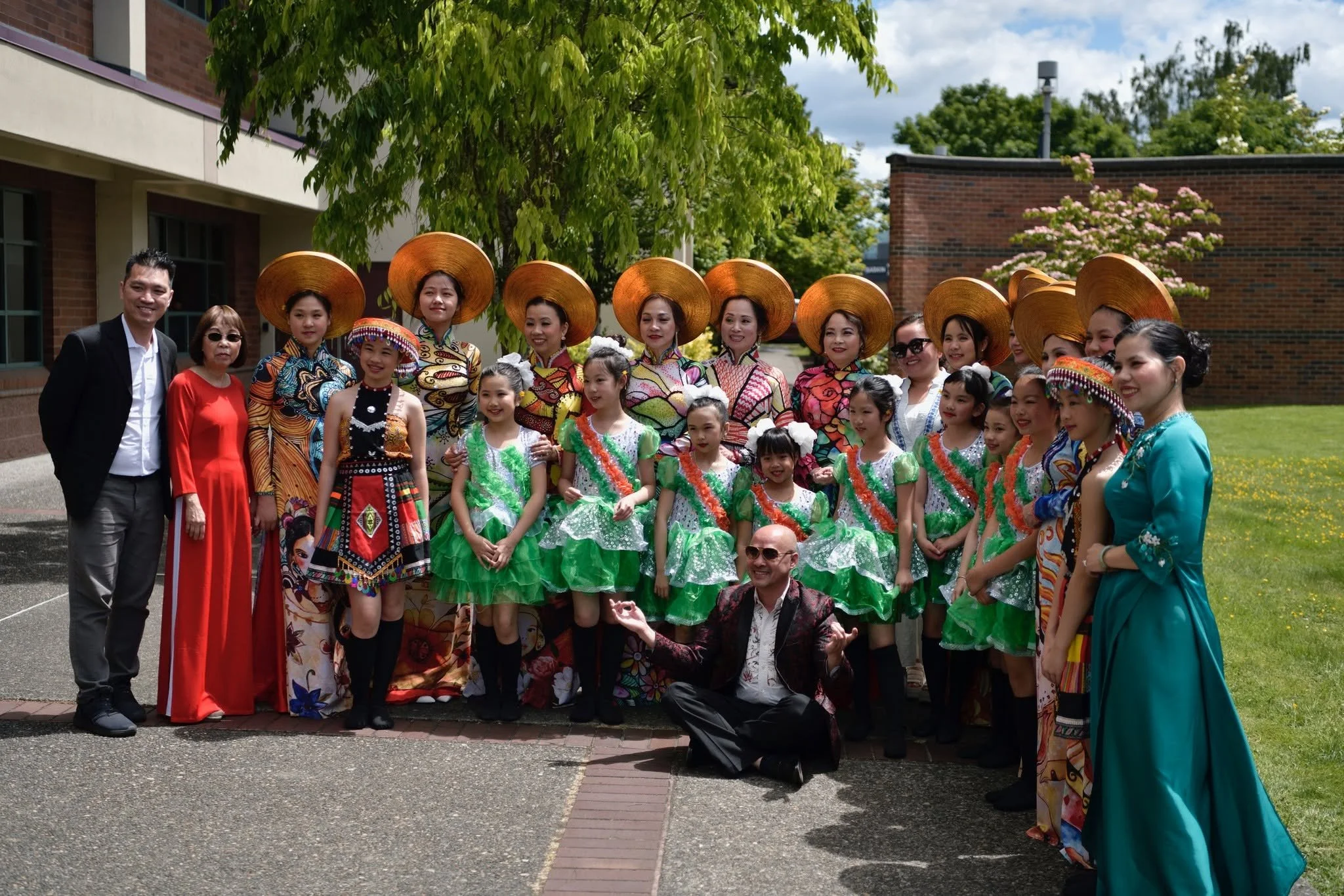 Multigenerational group in colorful traditional Vietnamese clothing posing outdoors at a cultural celebration