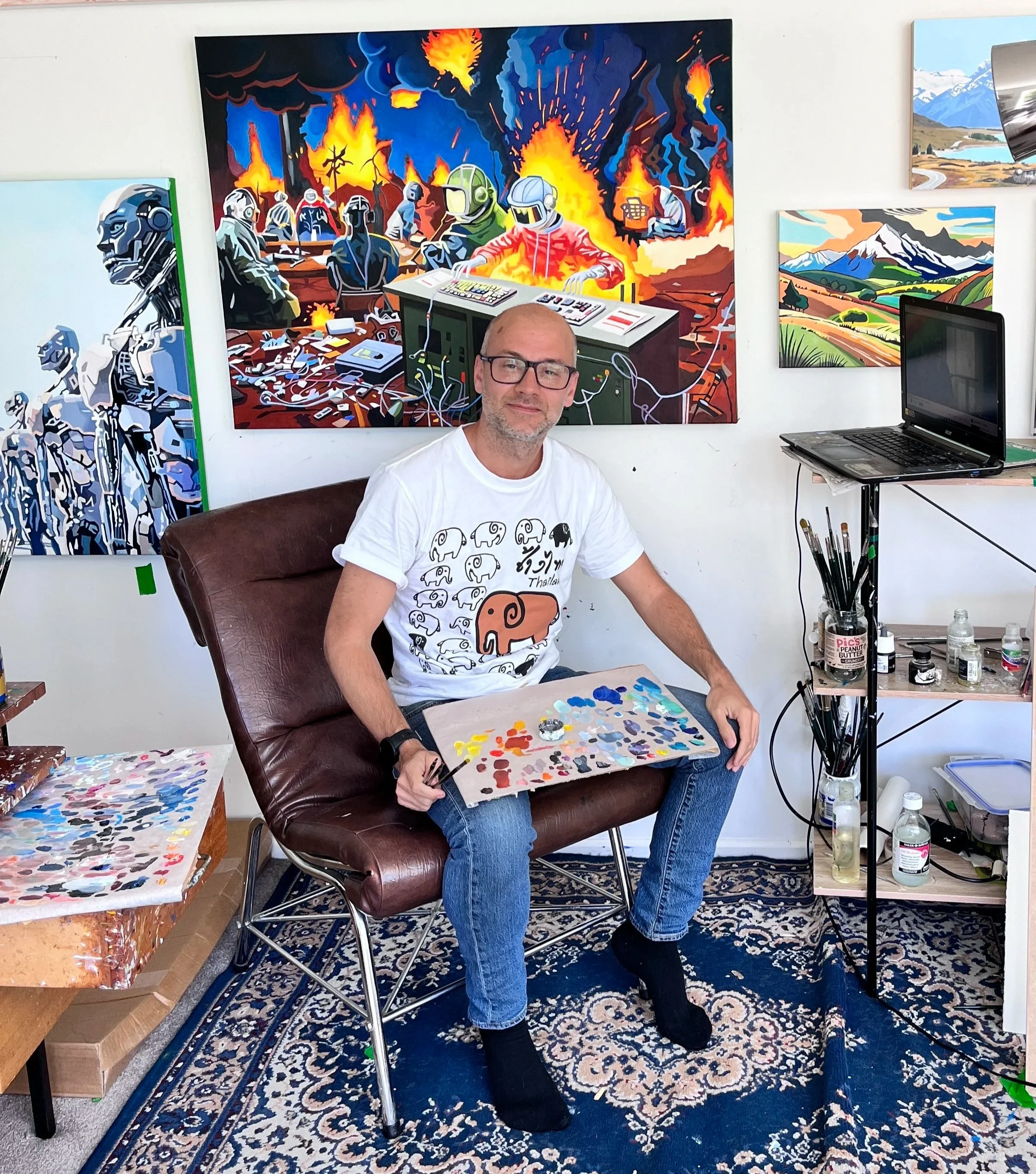 A man sitting in a chair with an art palette in his hand, surrounded by paintings of futuristic robots and landscapes of mountains and fields, in an art studio.