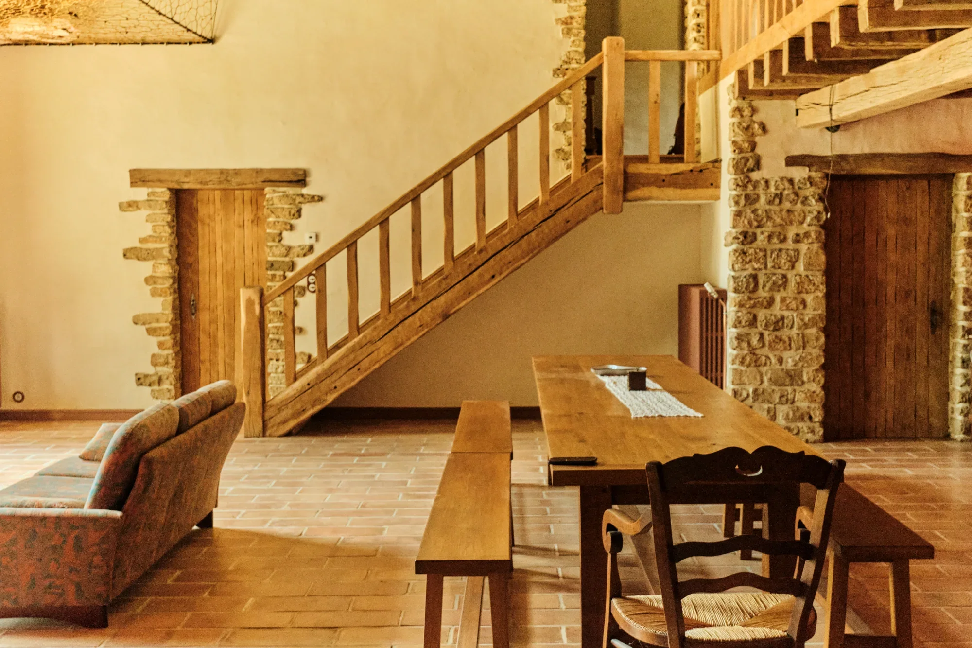 Salle à manger en pierre avec escalier en bois.