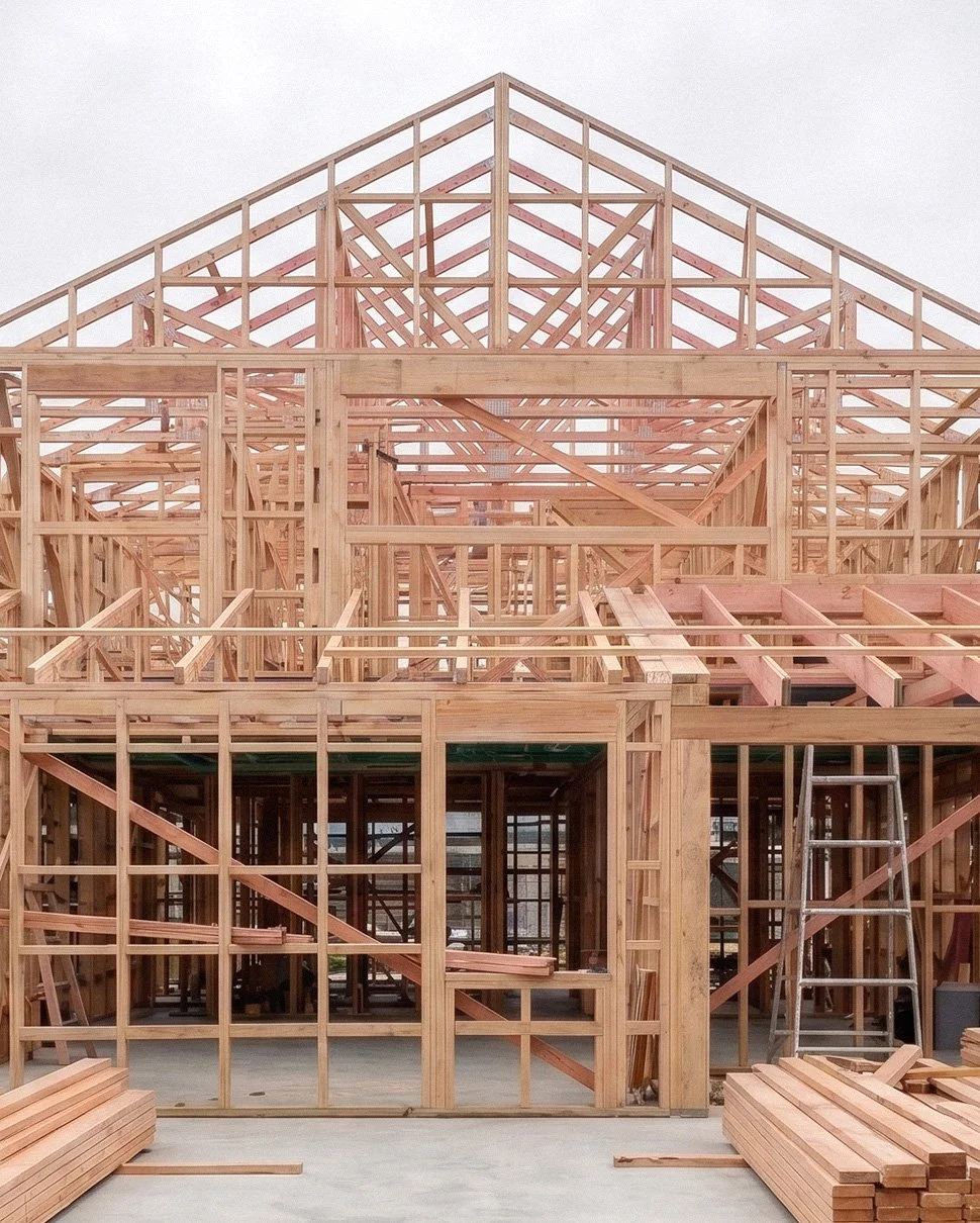 Timber house frame under construction with exposed roof and wall structures.