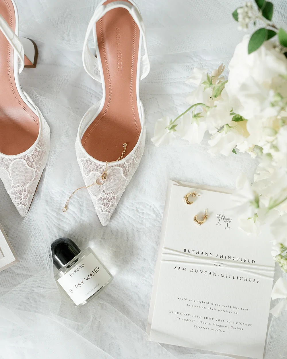 Bridal shoes and wedding invitations photographed on a veil