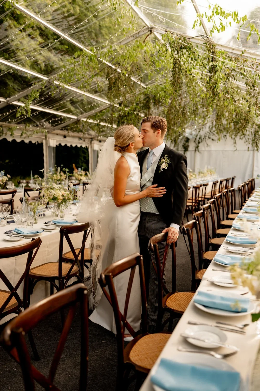 A wedding couple in their reception marquee which is filled with greenery