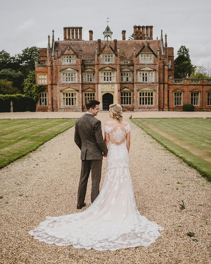 A newlywed couple walking towards their North Norfolk country house wedding venue