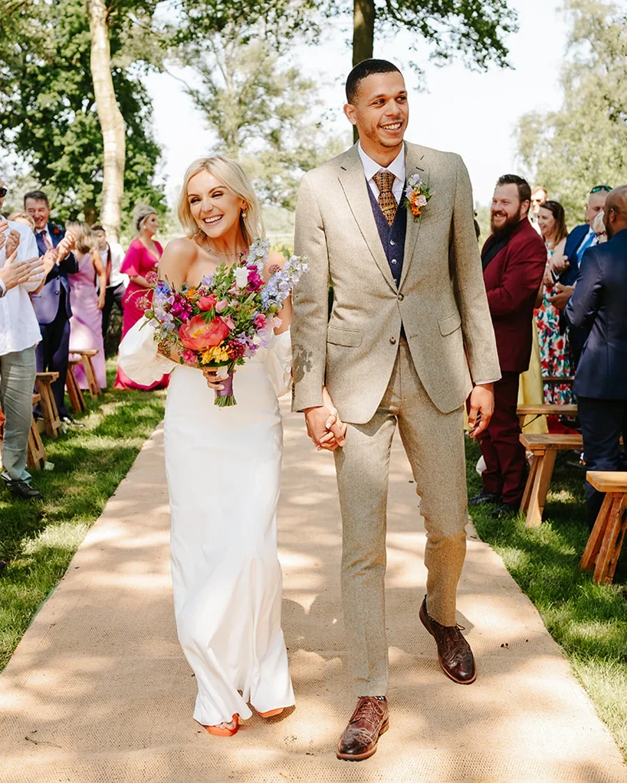 A wedding couple walking down the aisle of their woodland ceremony in East Anglia