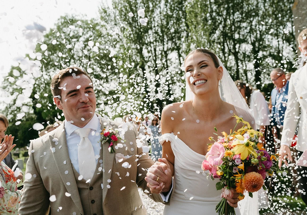 A happy wedding couple walking down the aisle with confetti being thrown