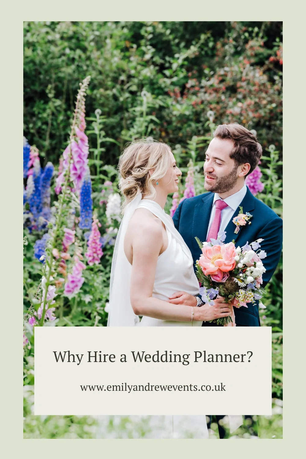 A newlywed couple in a garden filled with blooming foxgloves and delphiniums