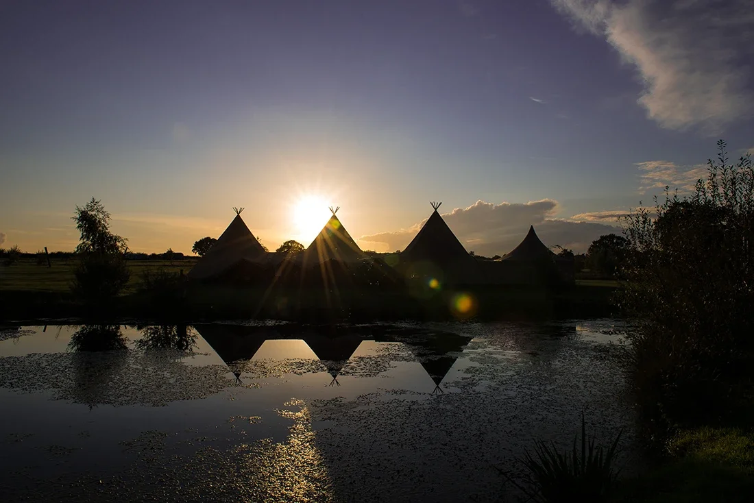 A triple wedding tipi in a meadow overlooking a lake