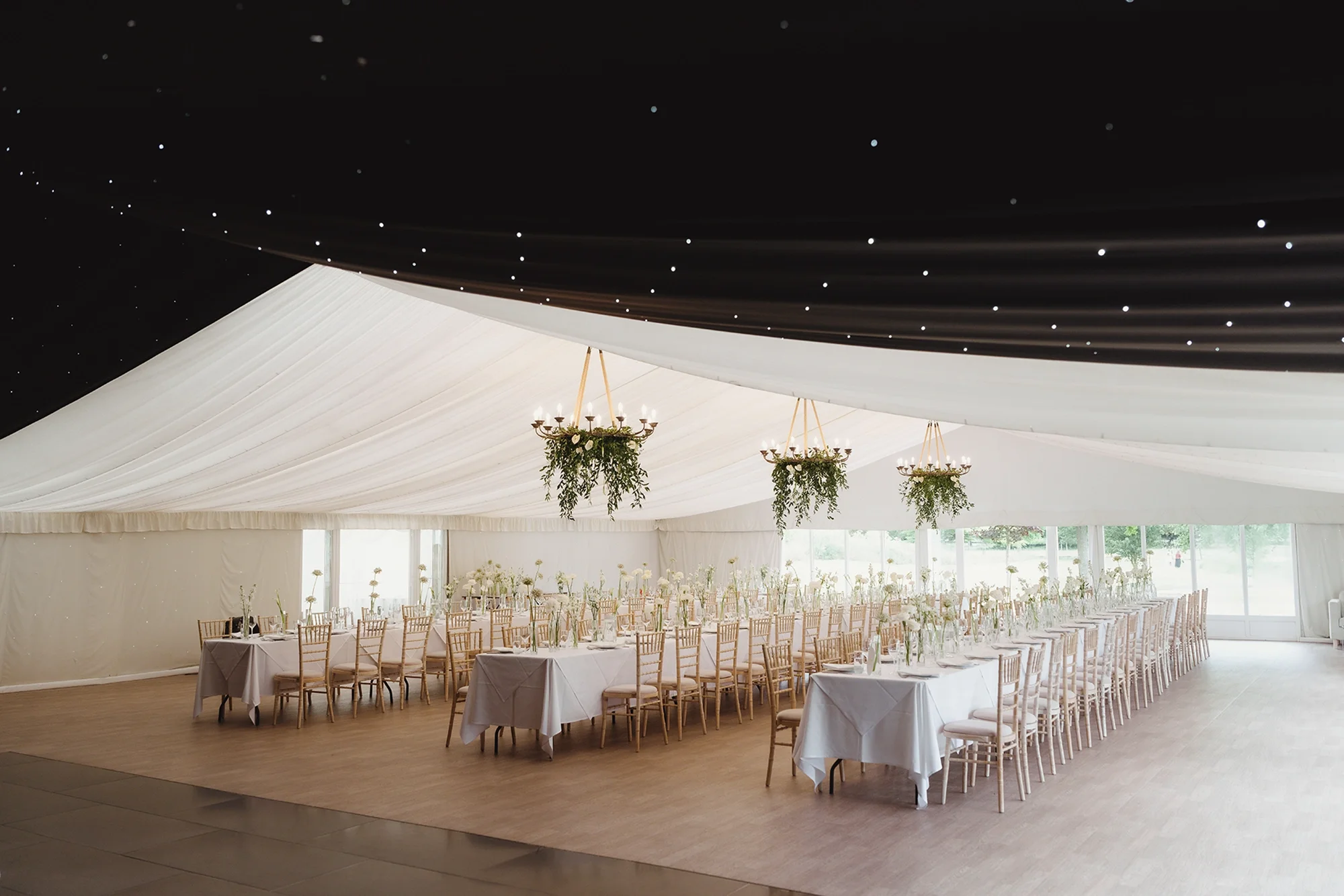 A wedding marquee with banqueting tables and a pea lit dancefloor area