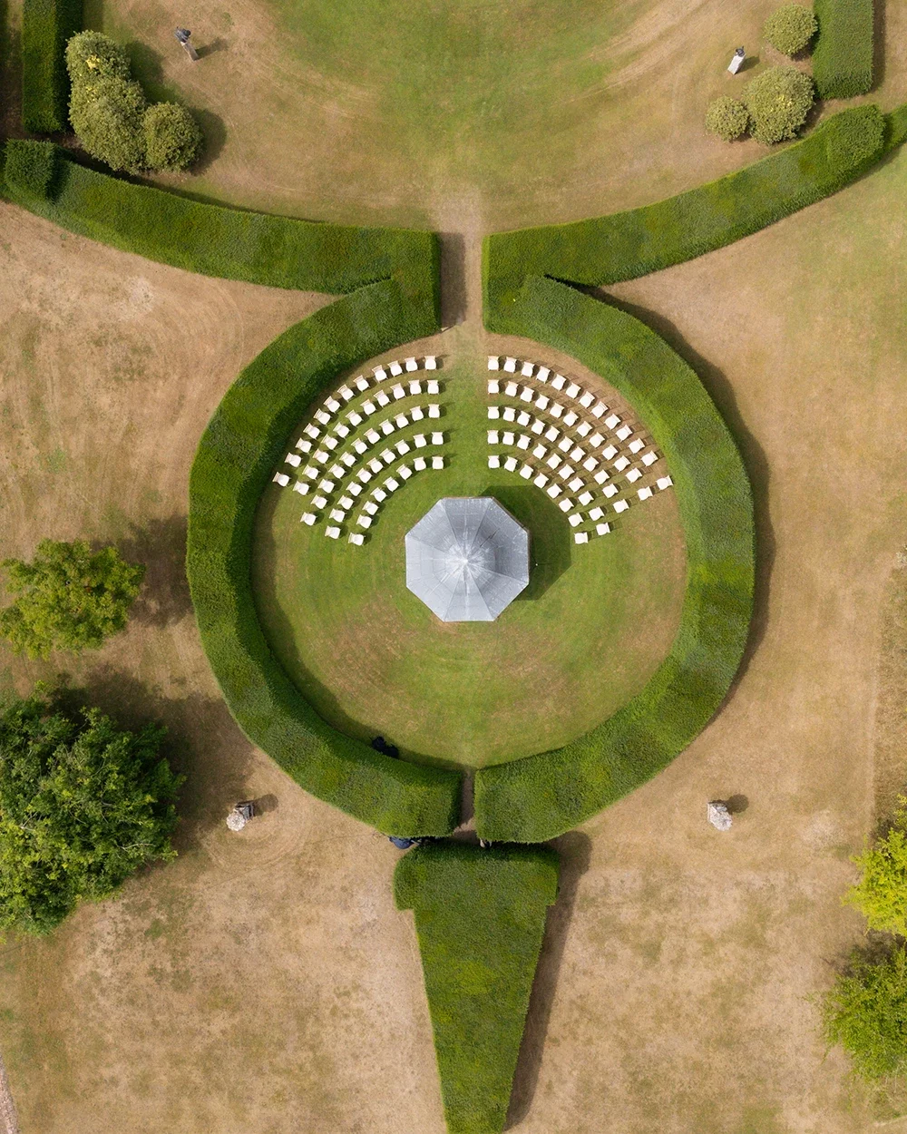 A wedding ceremony setup seen from above in a formal garden with box hedging