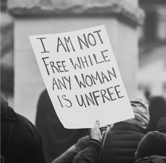A person holding a sign that reads, "I am not free while any woman is unfree," during a protest or rally.