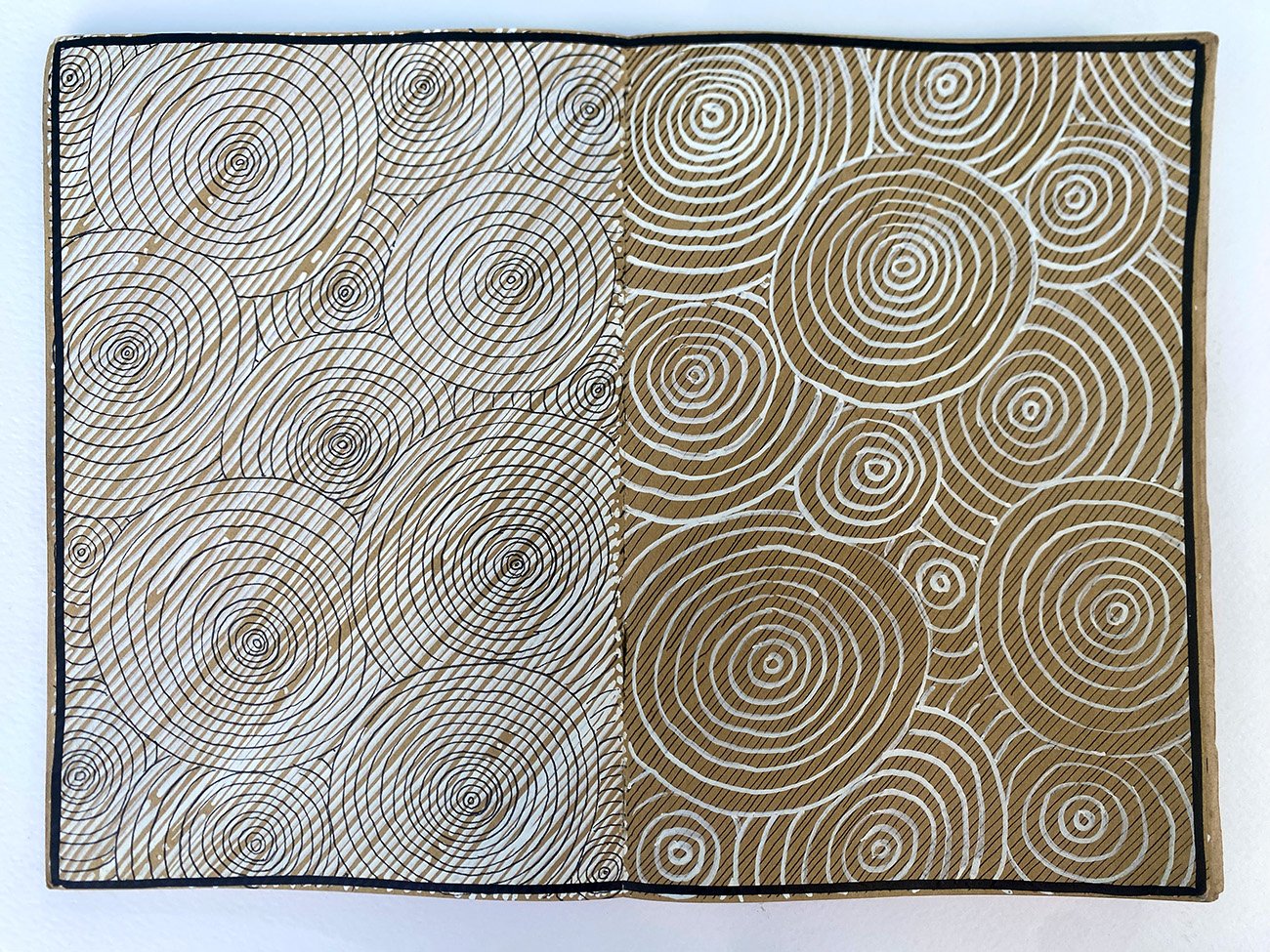 A piece of artwork featuring a pattern of concentric circles like rain on water in brown and white, divided diagonally to show two different shading styles.