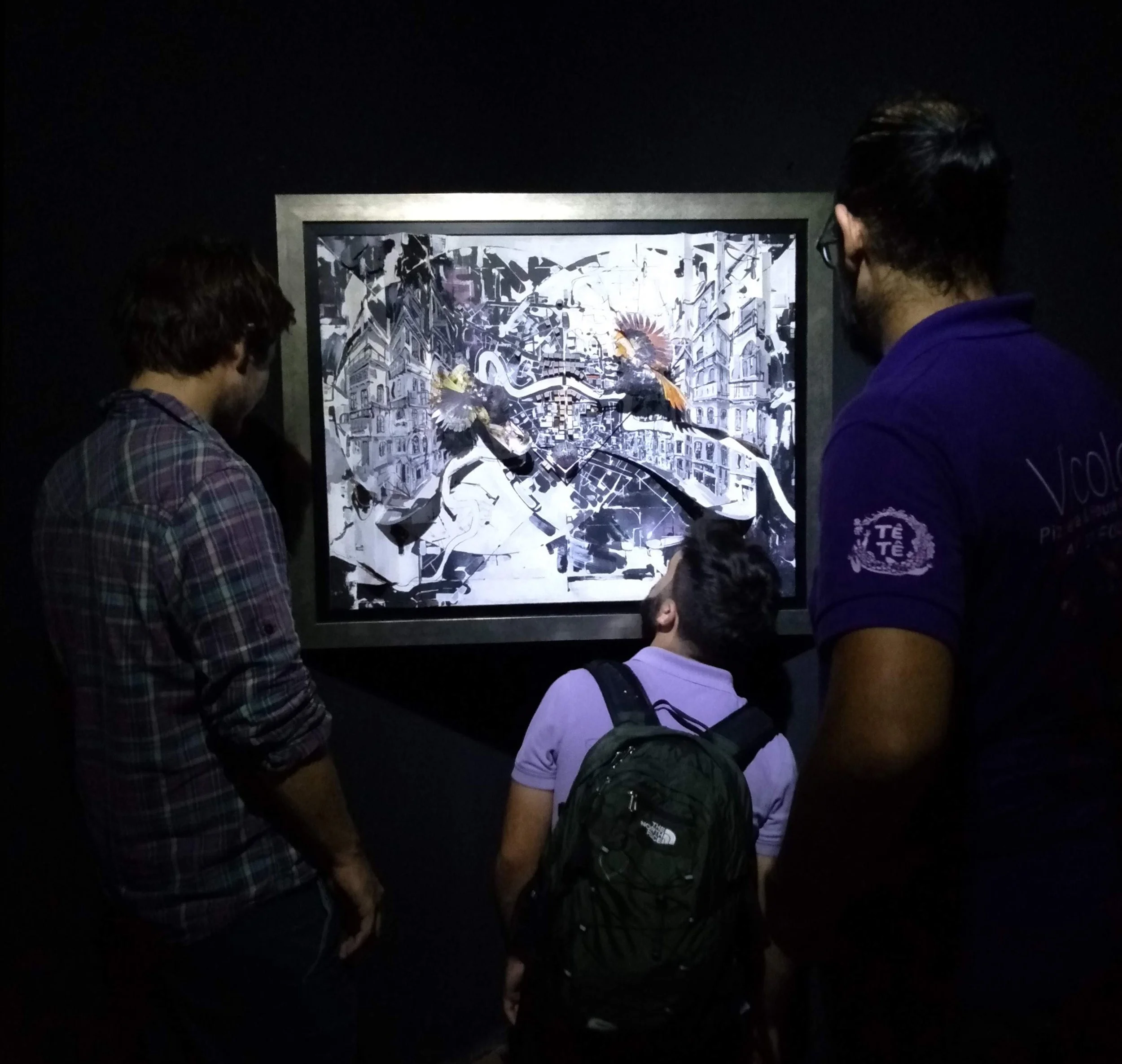 3 men looking at a black and white abstract cityscape paint on a black gallery wall