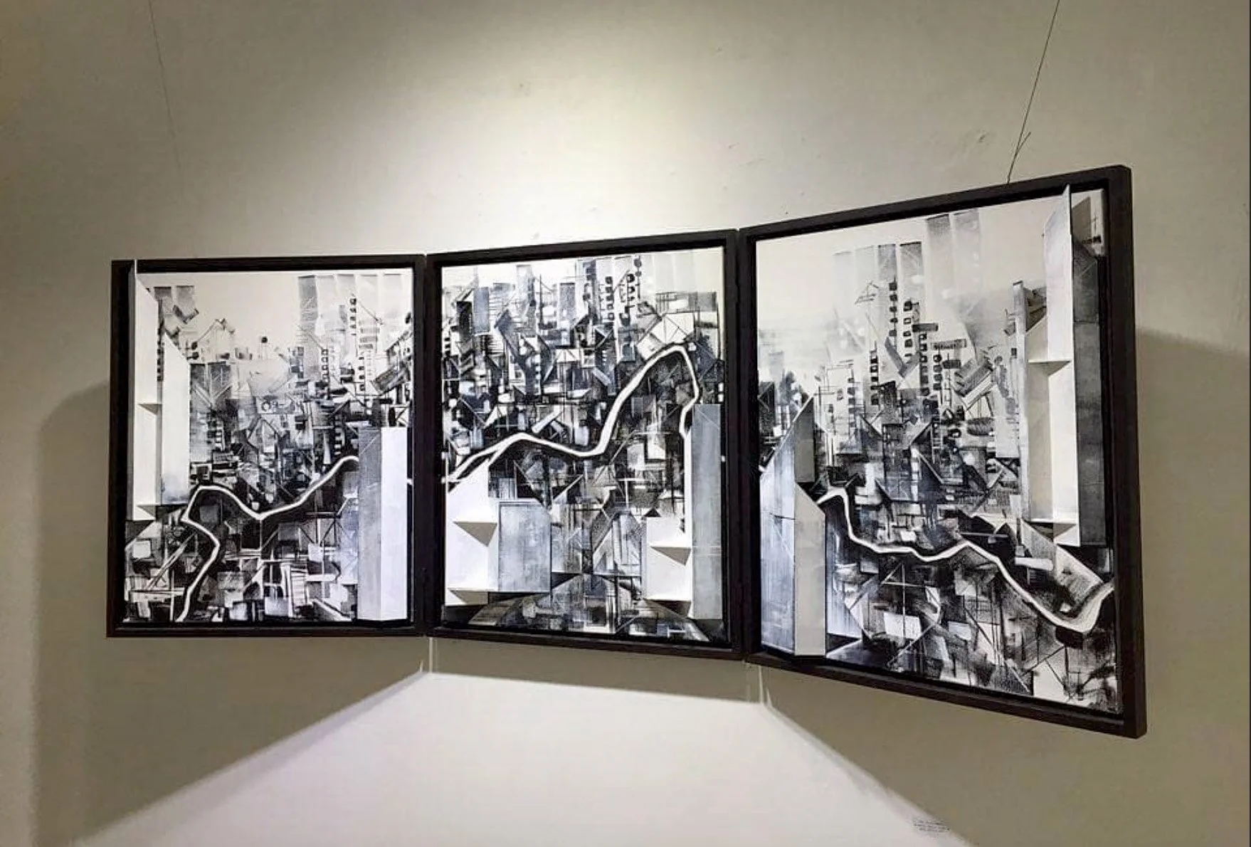black and white triptych painting of a city with a river through the center and sculptural 3D elements