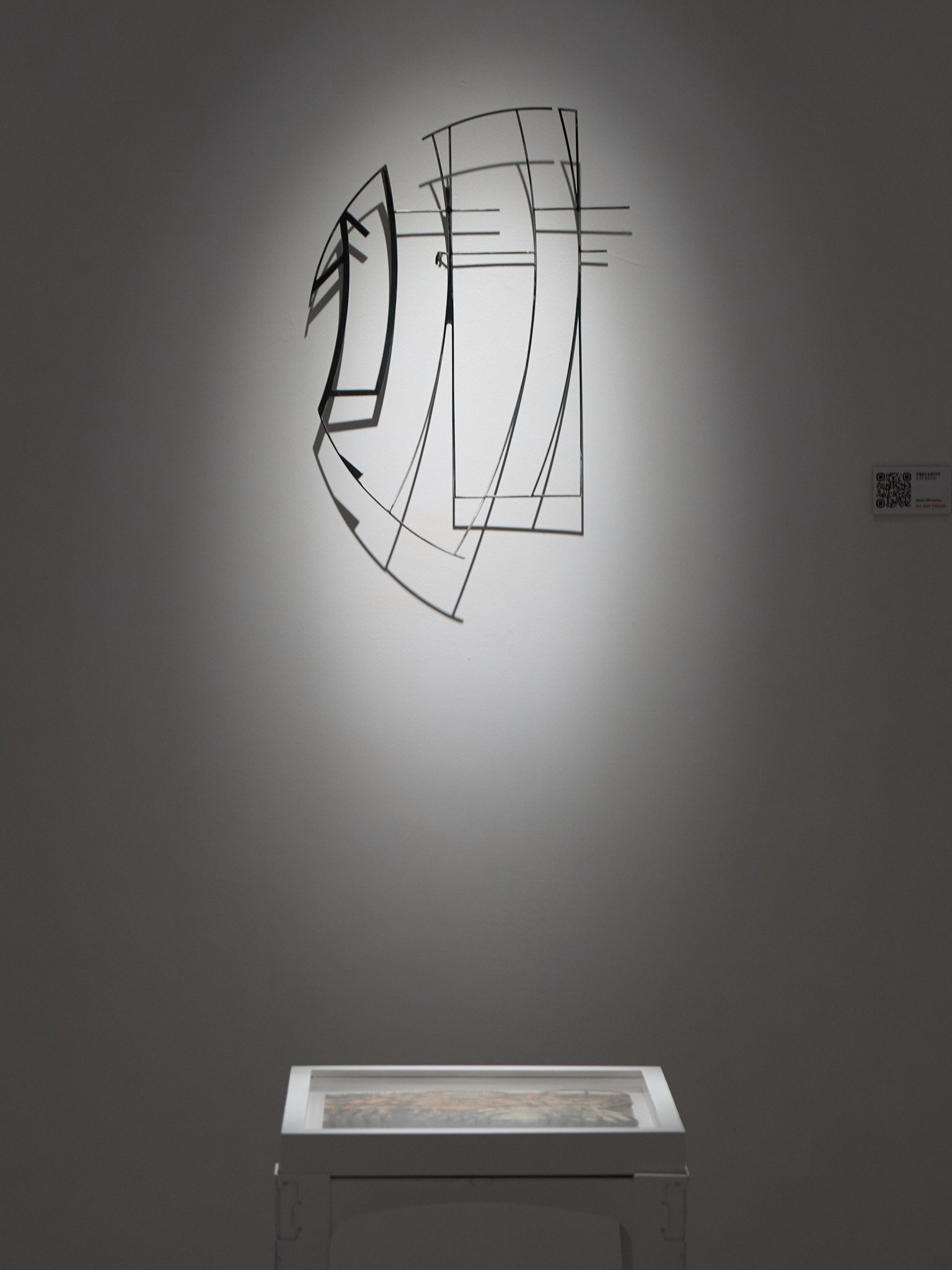 abstract geometric metal sculpture with thin lines over a small table