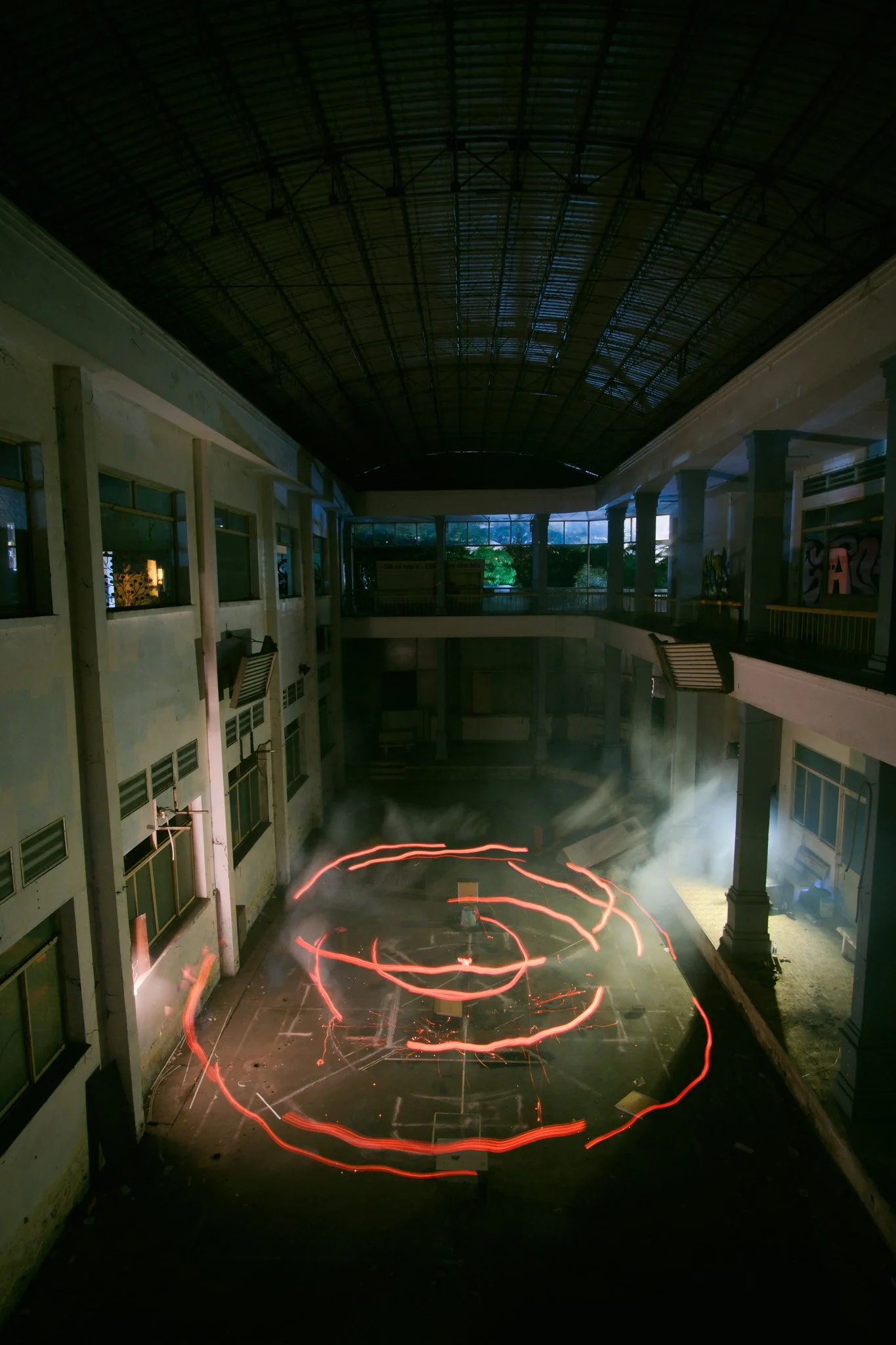 a man drawing a circle artwork with red light in an abandoned building at night