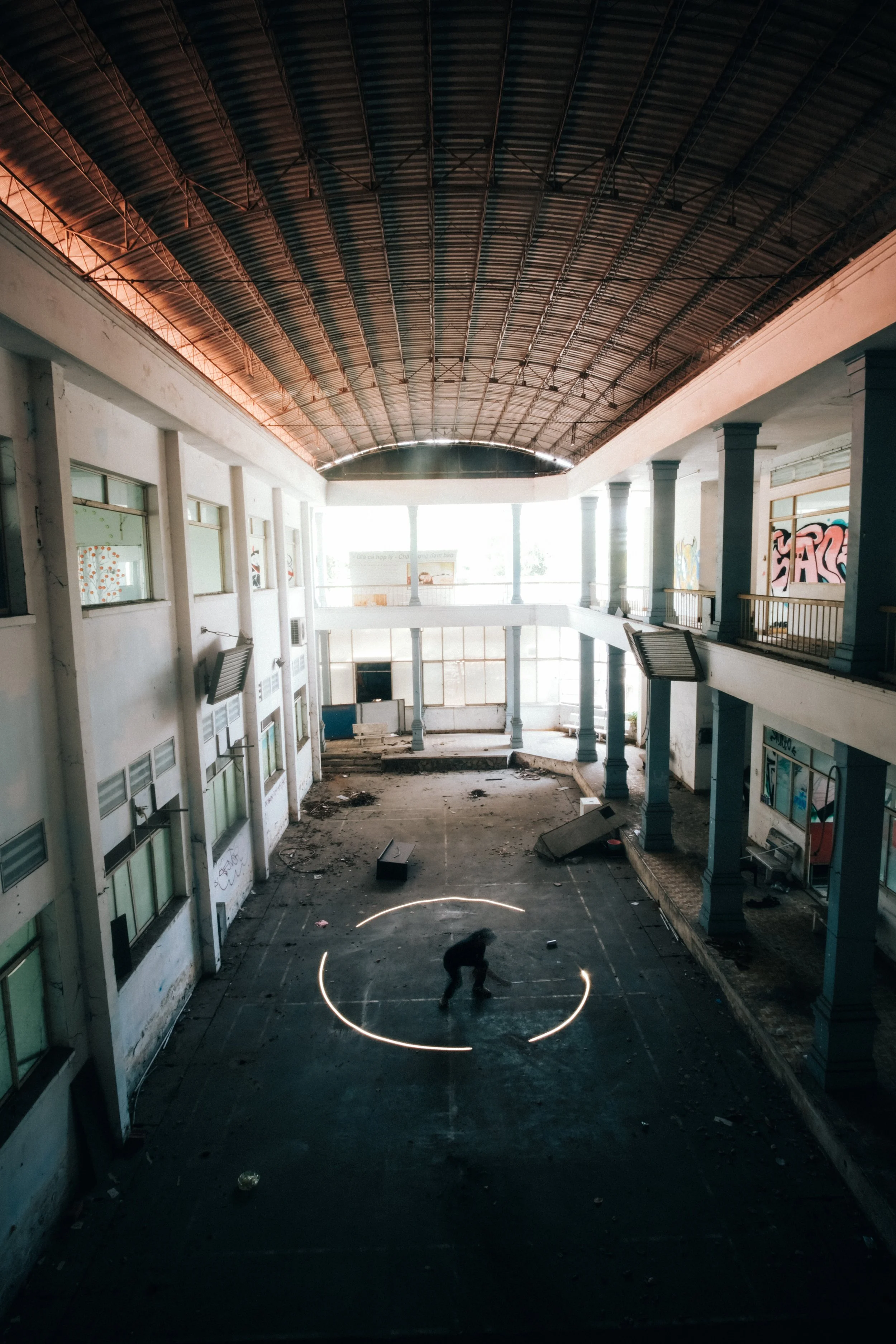a man drawing a circle artwork with white light in an abandoned building
