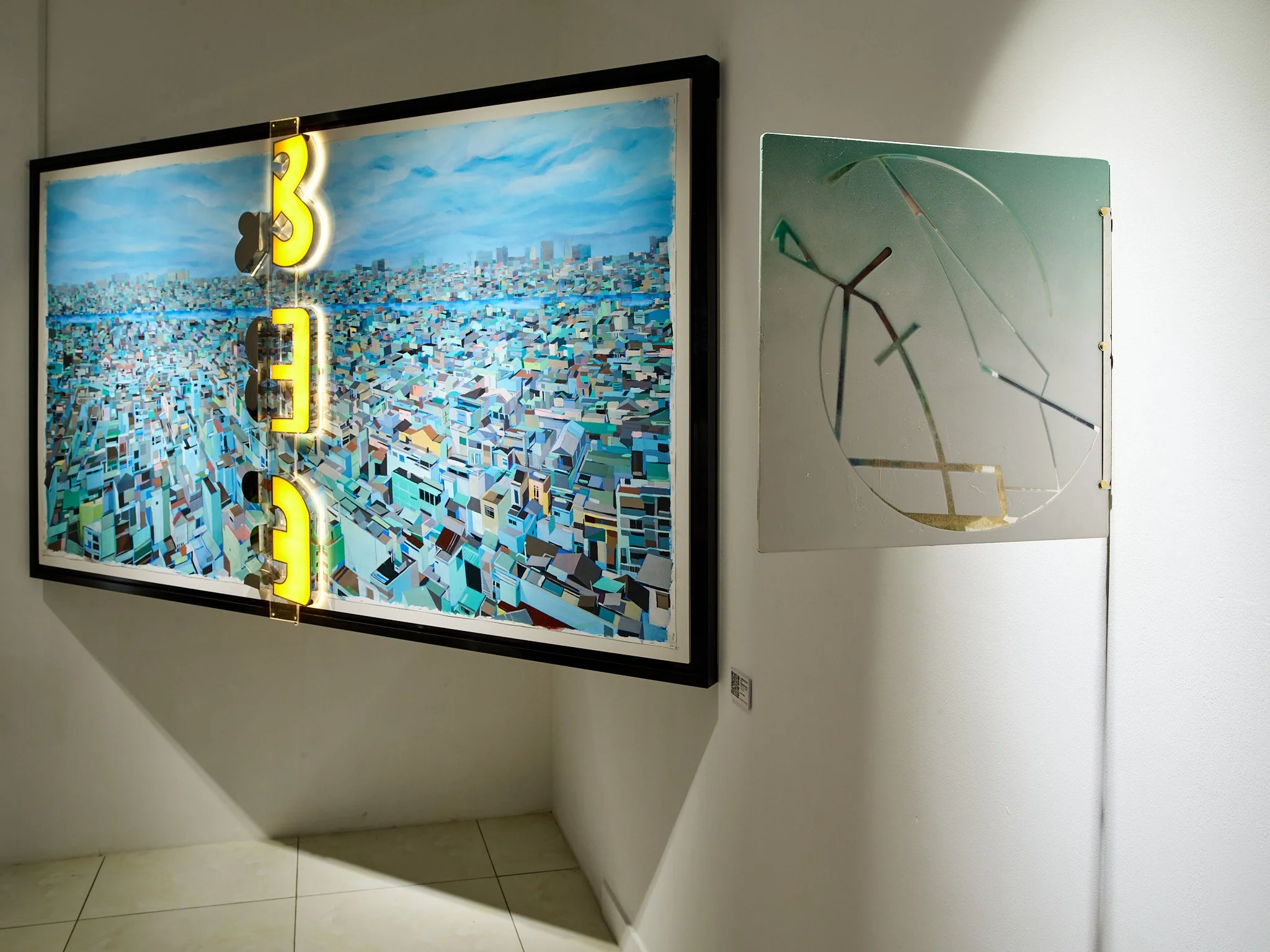 blue painting of rooftops with yellow sign and small abstract painting on the side