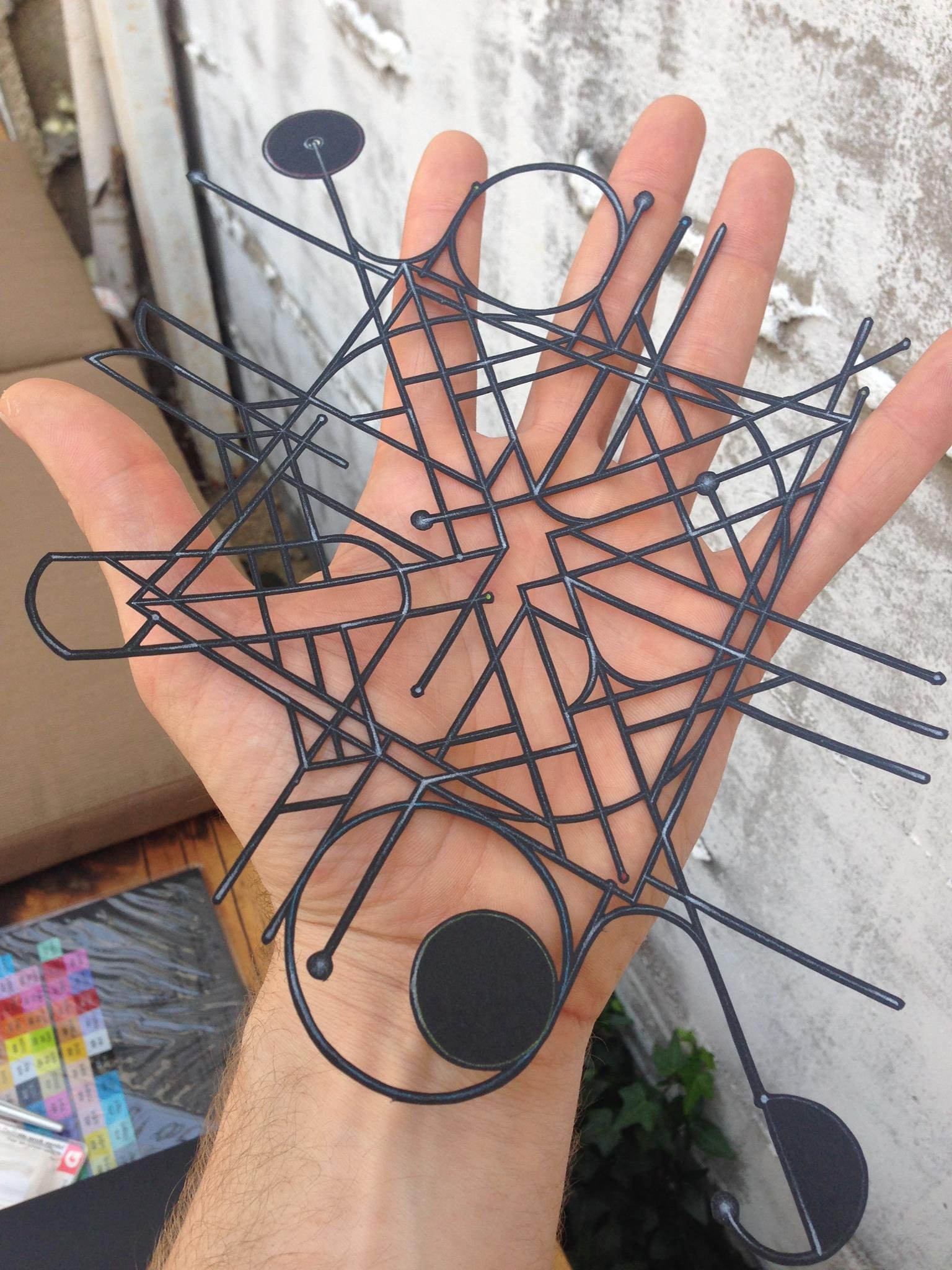 abstract geometric mandala artwork from finely cut black paper set in an open hand