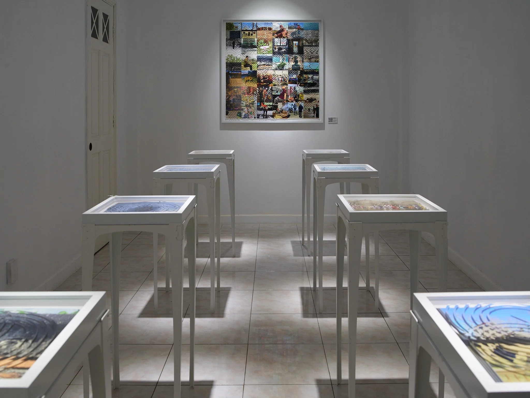 gallery filled with photo collages on tables with a large piece on the back wall like an alter