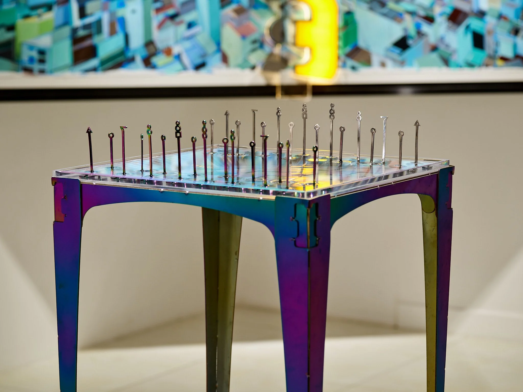 modern iridescent chess table filled with water and minimal looking abstract pieces in gallery space