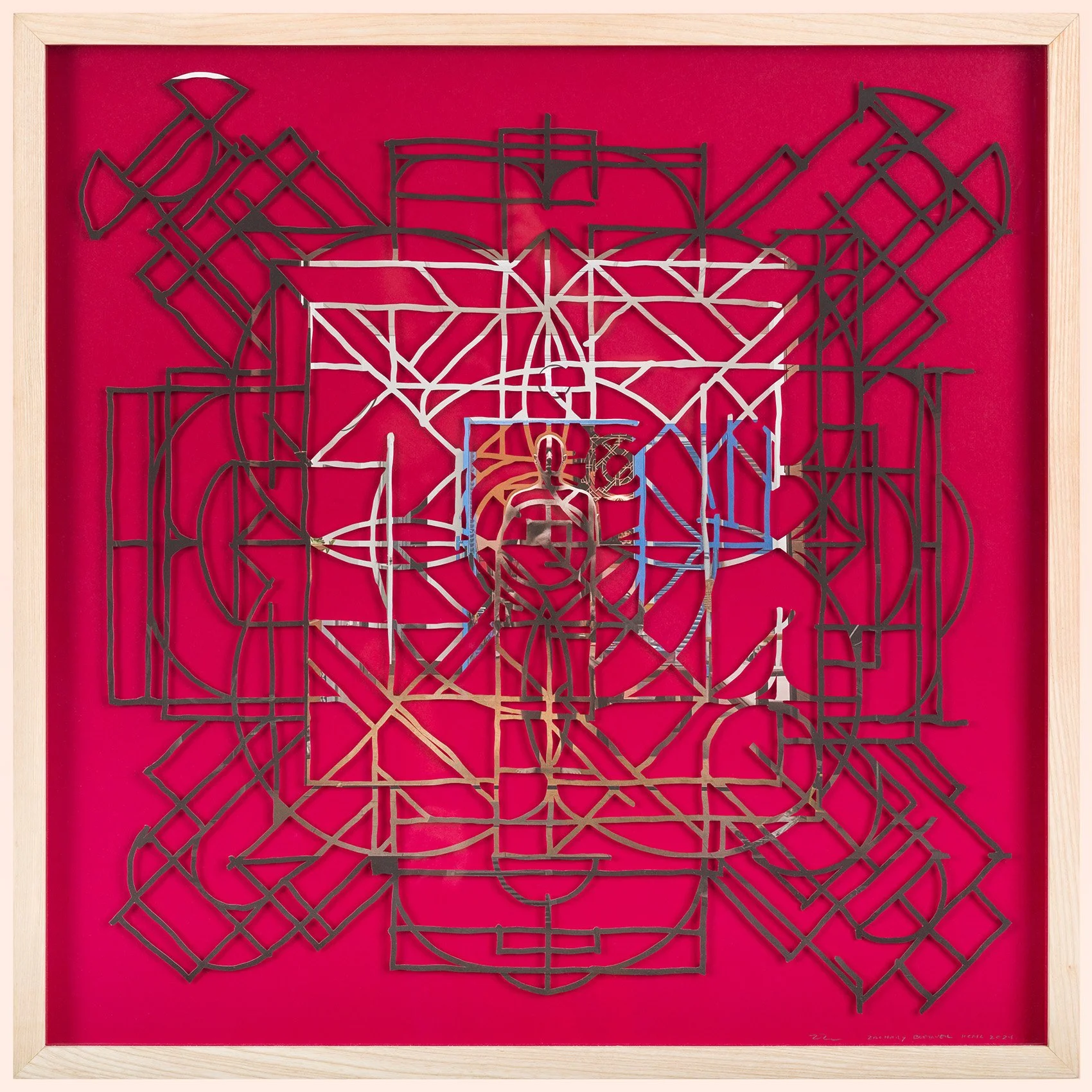 abstract geometric mandala artwork from cut photograph with centered figure on a red surface in wood frame