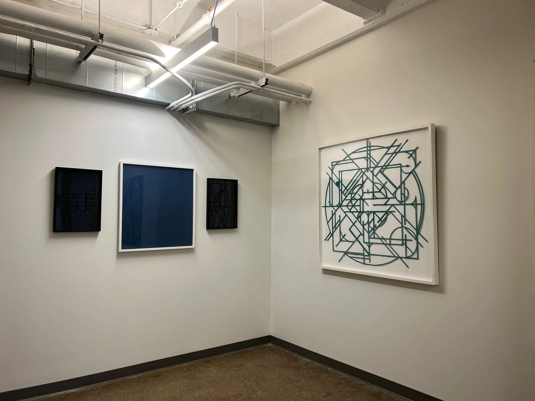 gallery space corner with four geometric abstract artworks 