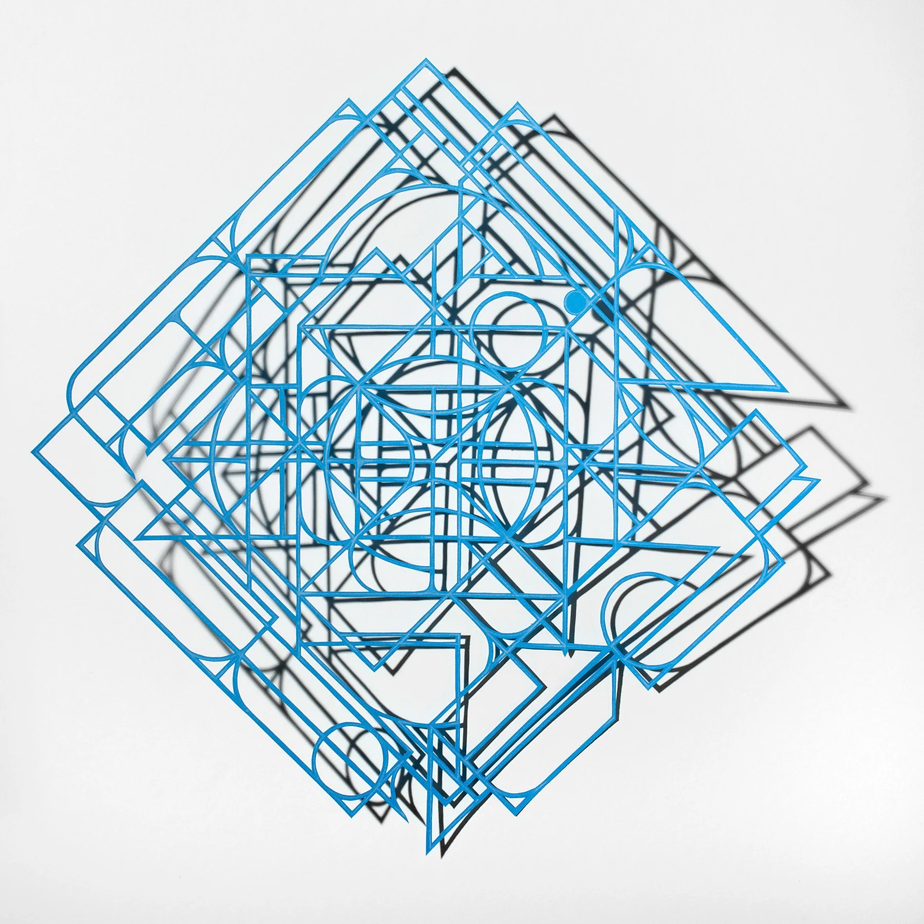 abstract geometric artwork made of finely cut blue paper casting a shadow on a white wall