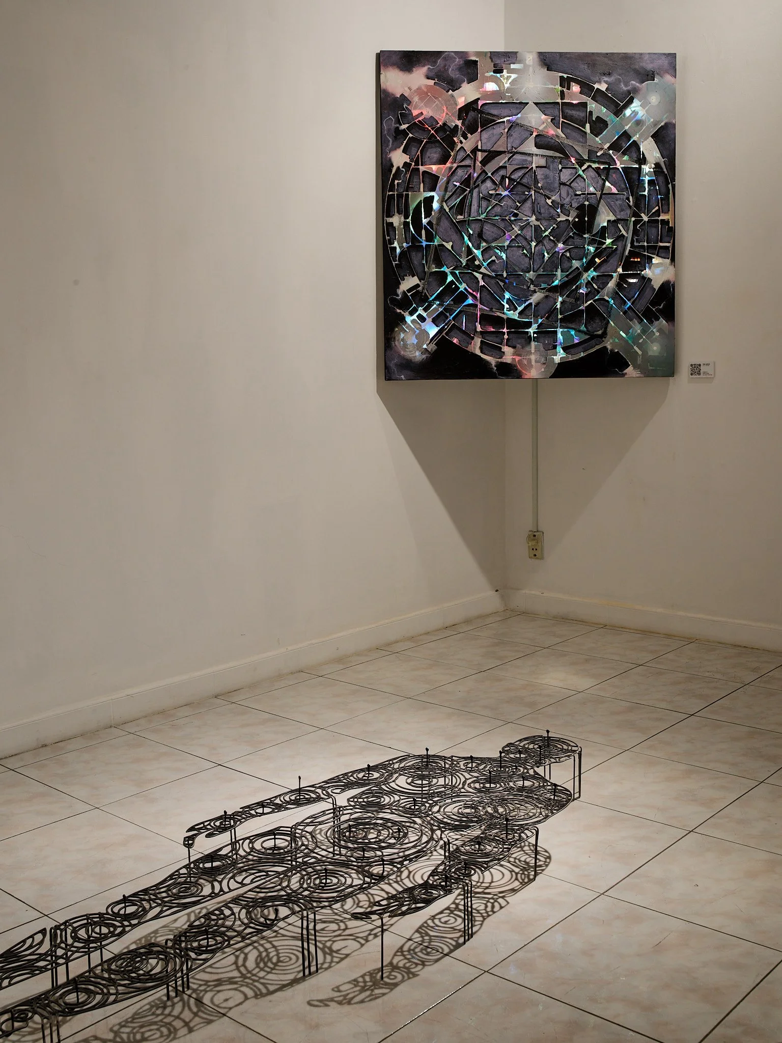 metal sculpture of a mans shadow made of rain drops on water in front of an abstract painting in a gallery