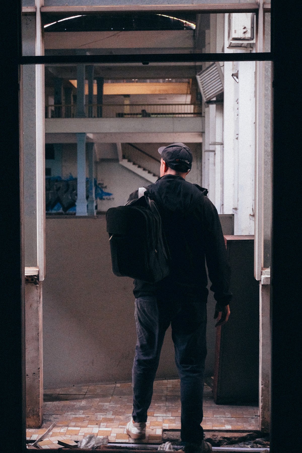 a man standing pensively in the doorway on an abandoned building about to enter