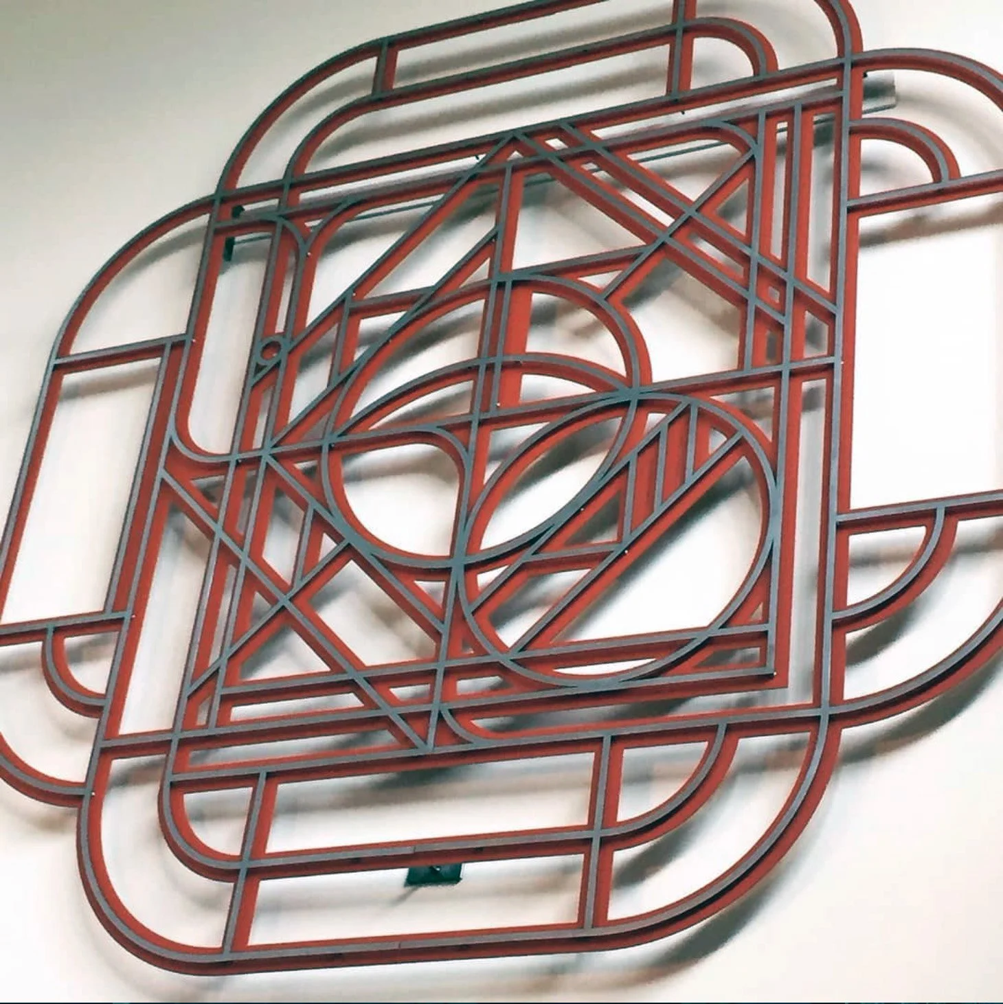 abstract geometric flat metal sculpture mandala mounted raised on a white wall