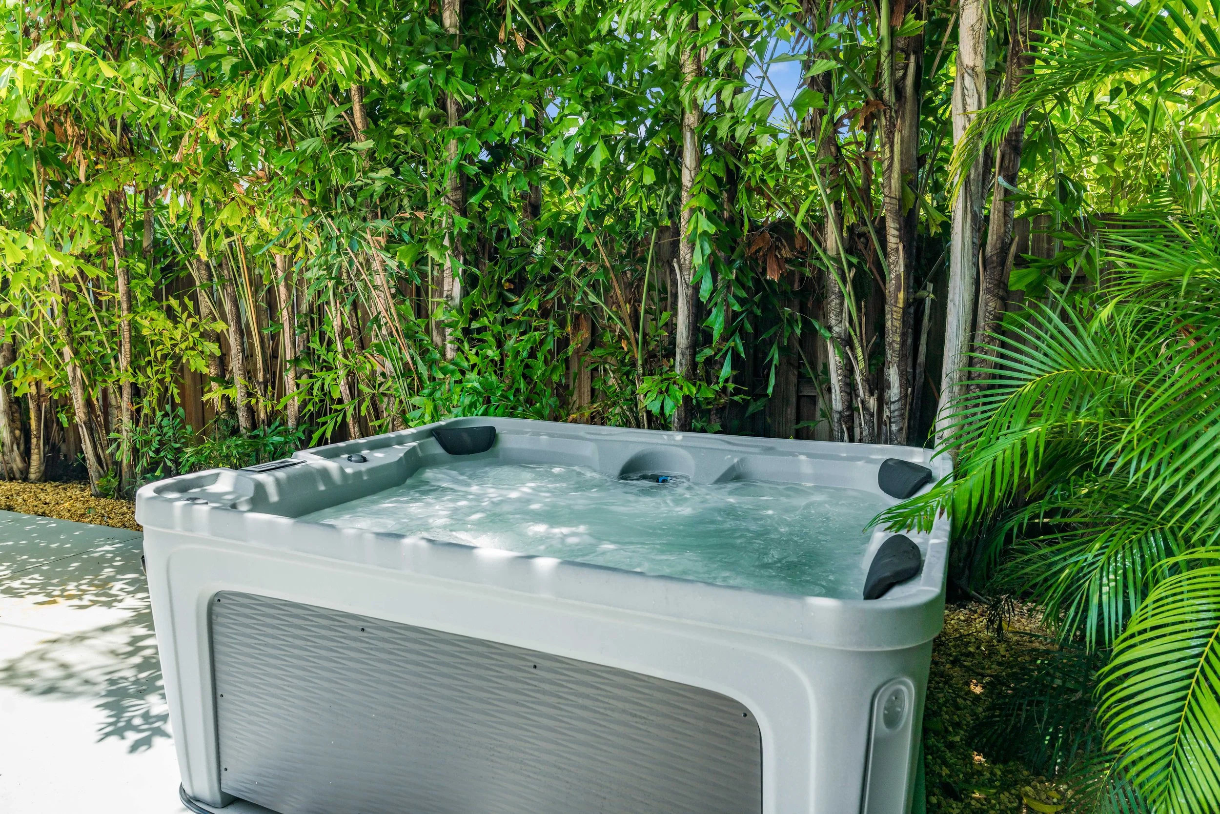 A hot tub or jacuzzi outdoors surrounded by lush green tropical plants and trees.