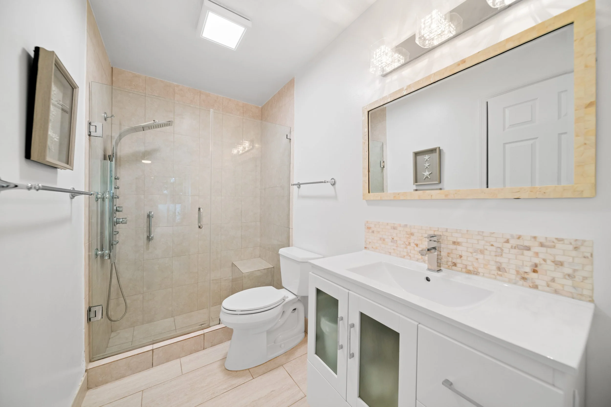 Bathroom with a walk-in shower, toilet, and white vanity with a mirror