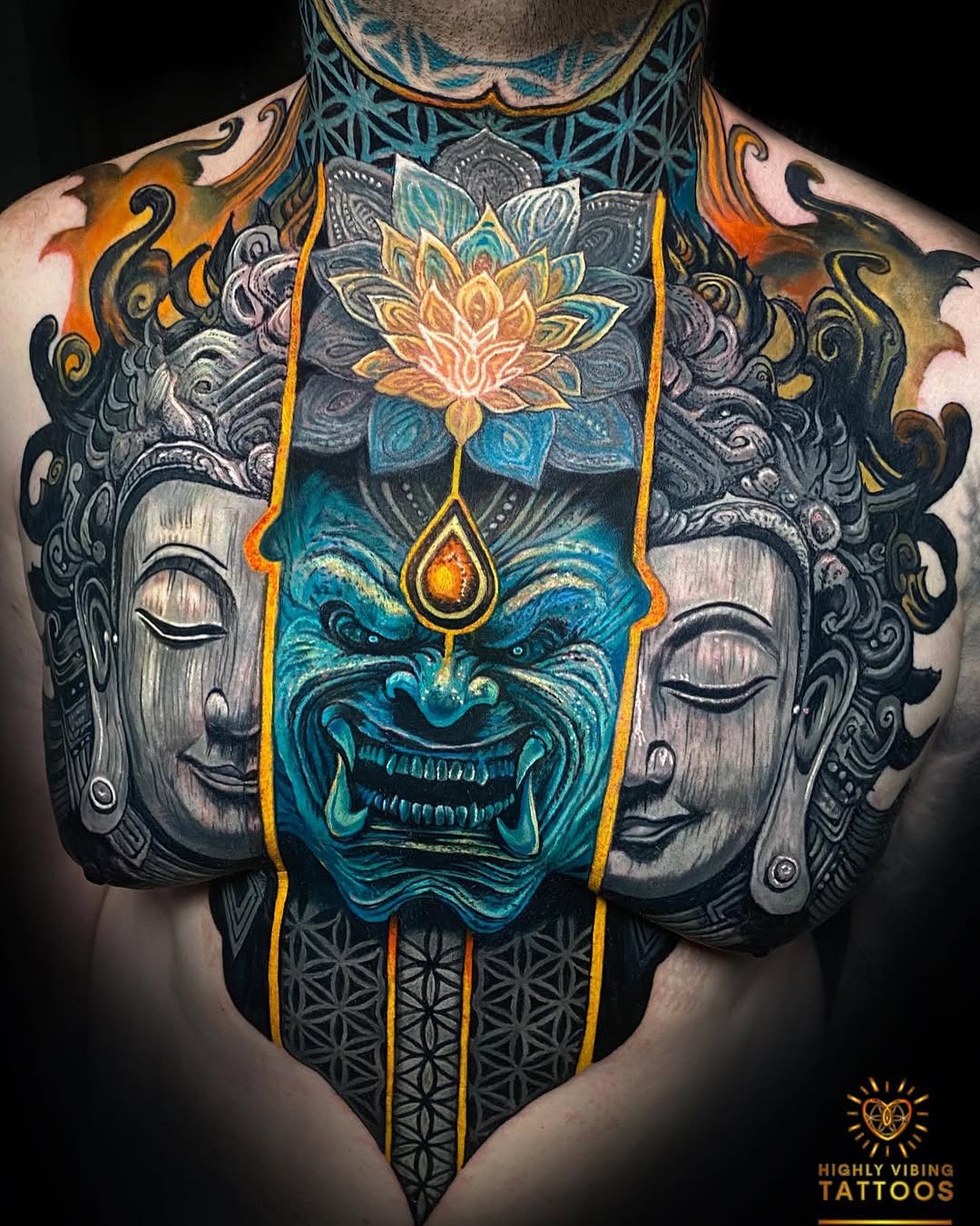Colorful tattoo with central blue face of a demon or mythological creature, flanked by two calm, peaceful Buddha faces on each side, with a lotus flower and decorative elements above. Daniel Armitage, Calgary Alberta, Surrealist Tattoo Artist, YYC