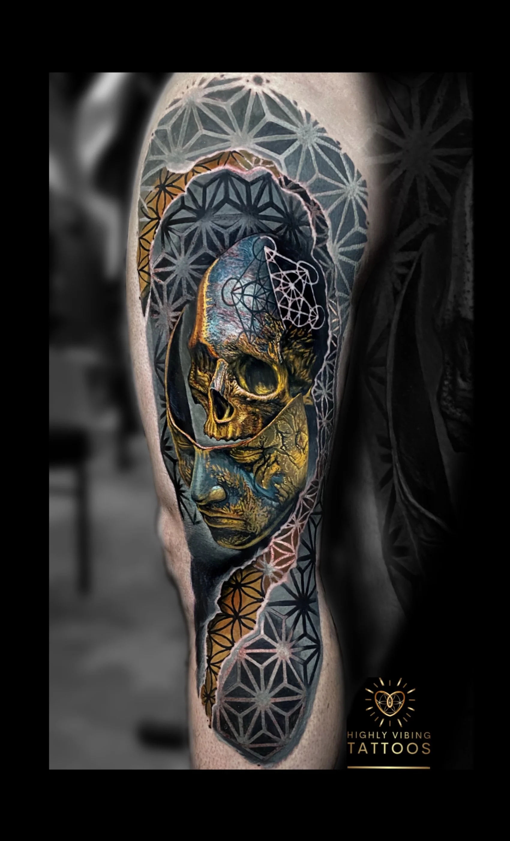 Colorful tattoo of a human skull with intricate geometric patterns, floral designs, and abstract elements on a person's arm. The tattoo includes vibrant colors like yellow, blue, and orange. Daniel Armitage, Calgary Alberta, Surrealist Tattoo Artist,