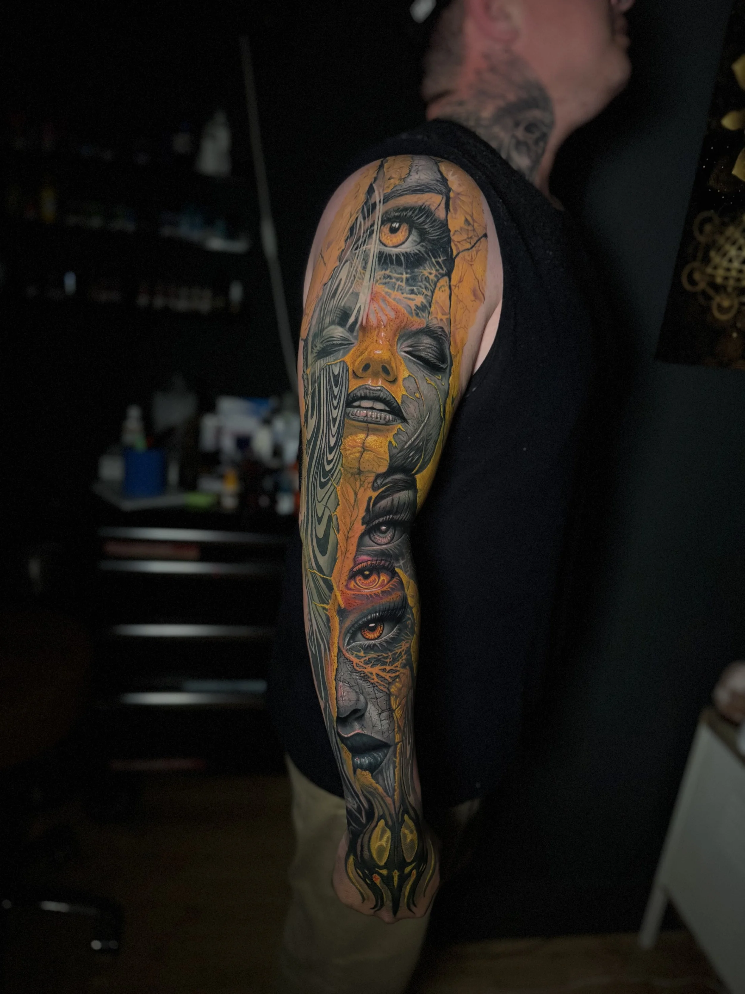 Daniel Armitage, Calgary Alberta, Surrealist Tattoo Artist, YYC Close-up of a colorful tattoo on a person's arm, depicting a woman's face with closed eyes, surrounded by abstract patterns and vibrant colors.