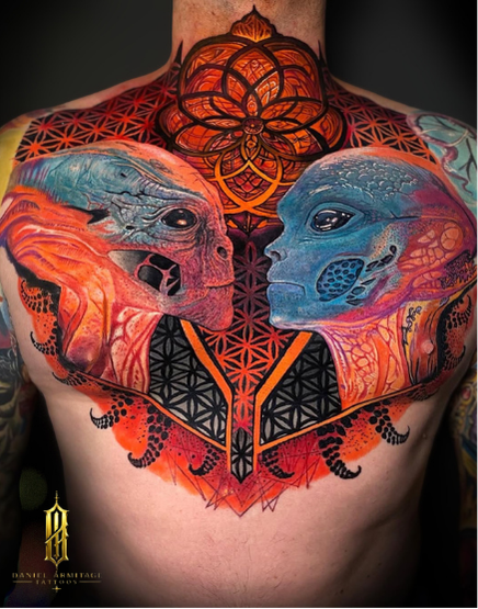 Daniel Armitage, Calgary Alberta, Surrealist Tattoo Artist, YYC Colorful chest tattoo of two dinosaur faces, one orange and the other blue, facing each other with geometric and mandala patterns above and below.