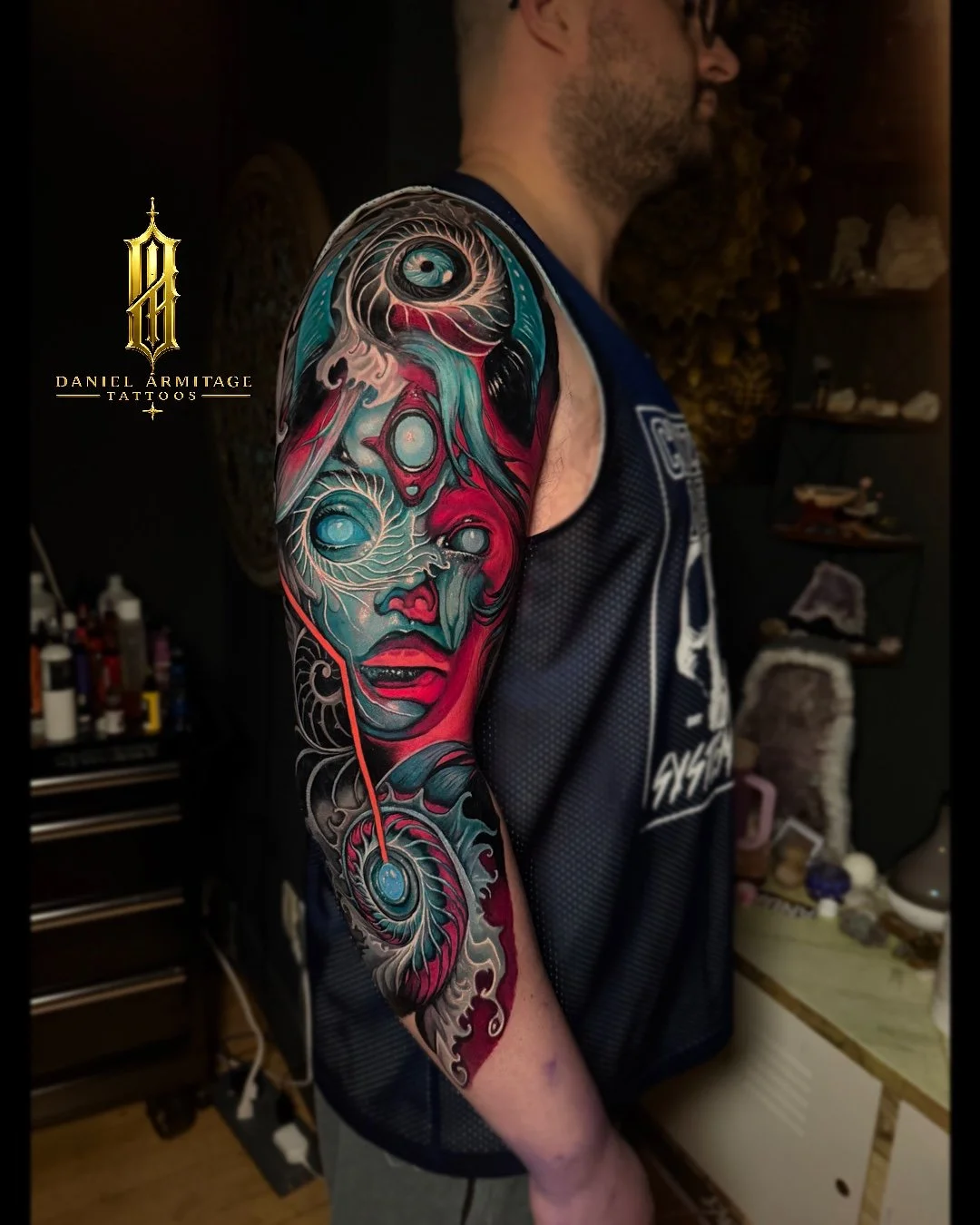 Daniel Armitage, Calgary Alberta, Surrealist Tattoo Artist, YYC Colorful tattoo sleeve featuring abstract faces, swirling patterns, and vibrant colors on a man's upper arm.