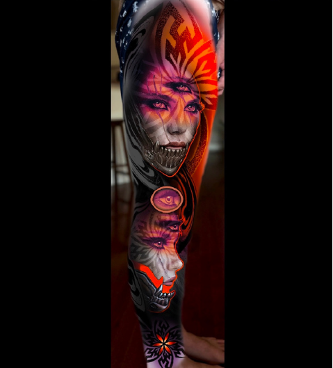 Tattoo sleeve featuring a large, detailed face of a woman with purple eyes, surrounded by abstract sun, moon, lips, and skull designs in black, red, orange, and purple colors. Daniel Armitage, Calgary Alberta, Surrealist Tattoo Artist, YYC