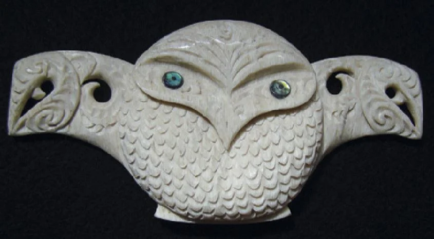Owl carving with outstretched wings carved as manaia faces