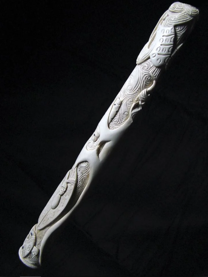 This pōrutu is carved as a kaitiaki of the families of taonga puoro, and it portrays a number of significant traditional beings associated with them, holding tightly to their treasures. It is carved from the leg bone of an ostrich, which was used as…